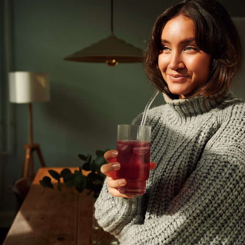 Smiling woman drinking from a glass in a retro-inspired kitchen for Drinkerie.